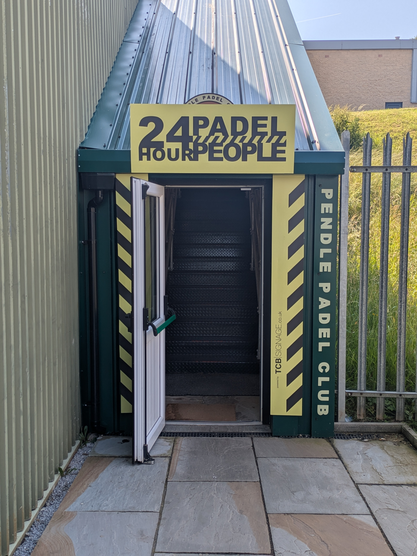 24 Hour Padel People branded entrance signage at Pendle Padel Club with yellow and black Factory Records-inspired design