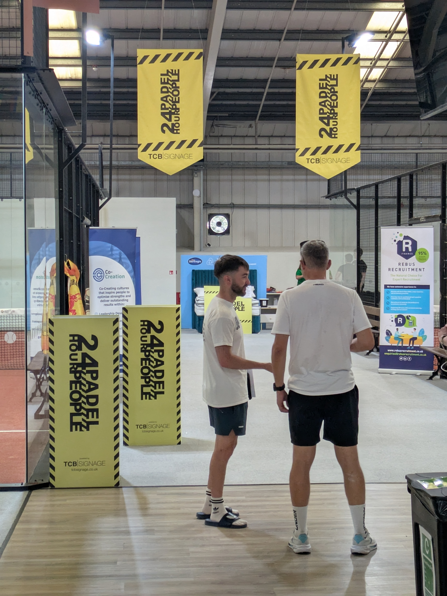 24 Hour Padel People hanging banners and floor totems inside Pendle Padel Club during the charity event