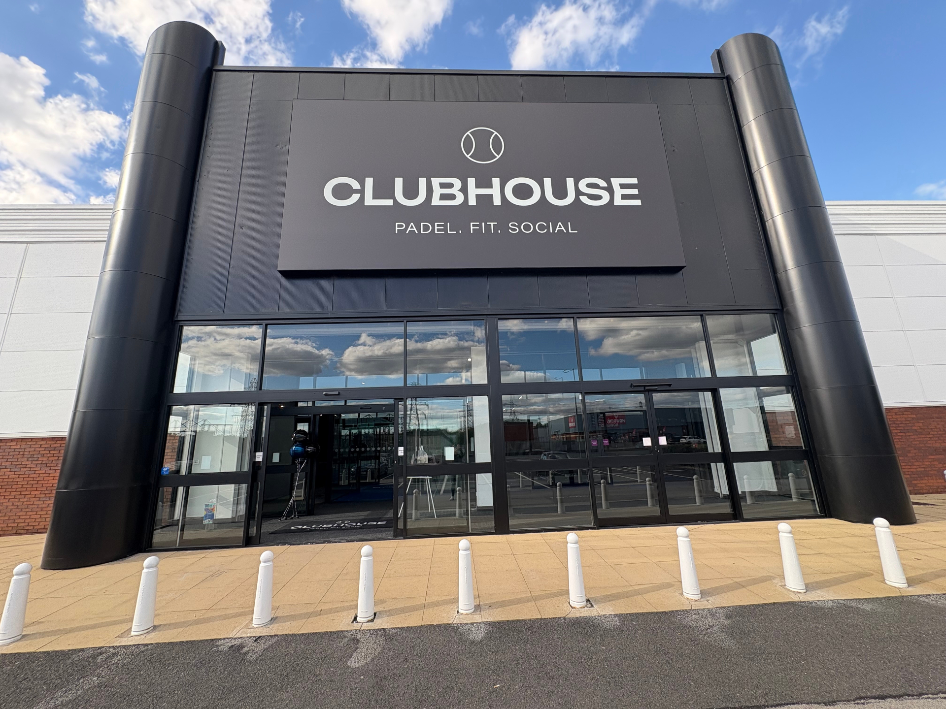 Clubhouse padel club large fascia sign with white logo and lettering on a black panel above the entrance