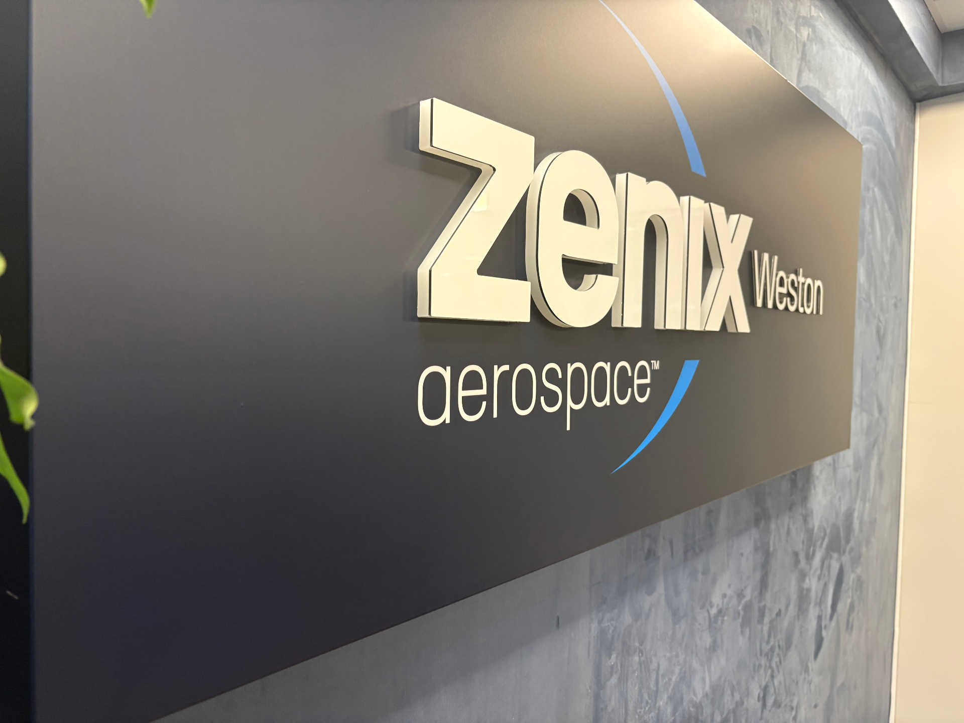 Zenix Aerospace push-through LED illuminated reception light box with white 3D letters on a dark panel