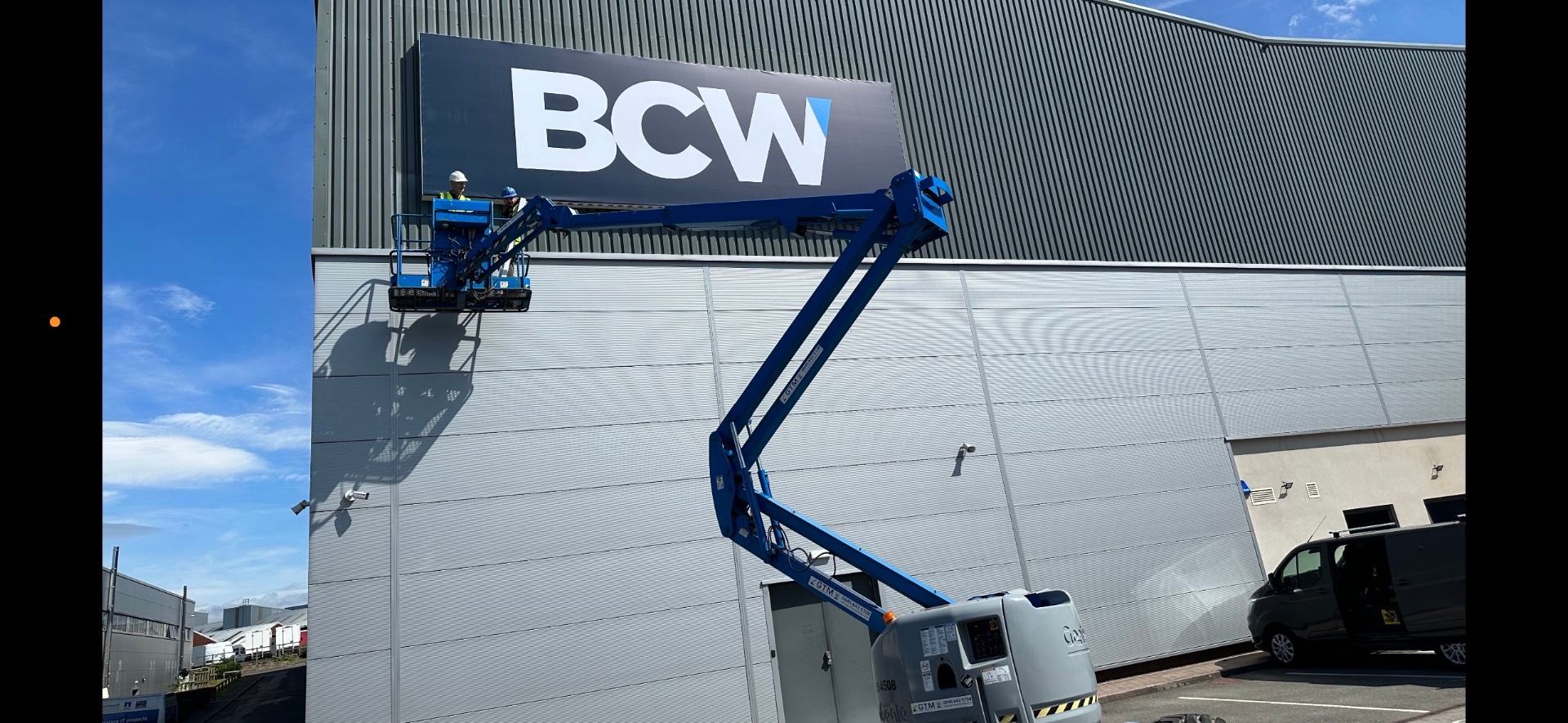 BCW exterior building signage being installed from a cherry picker on a large industrial unit