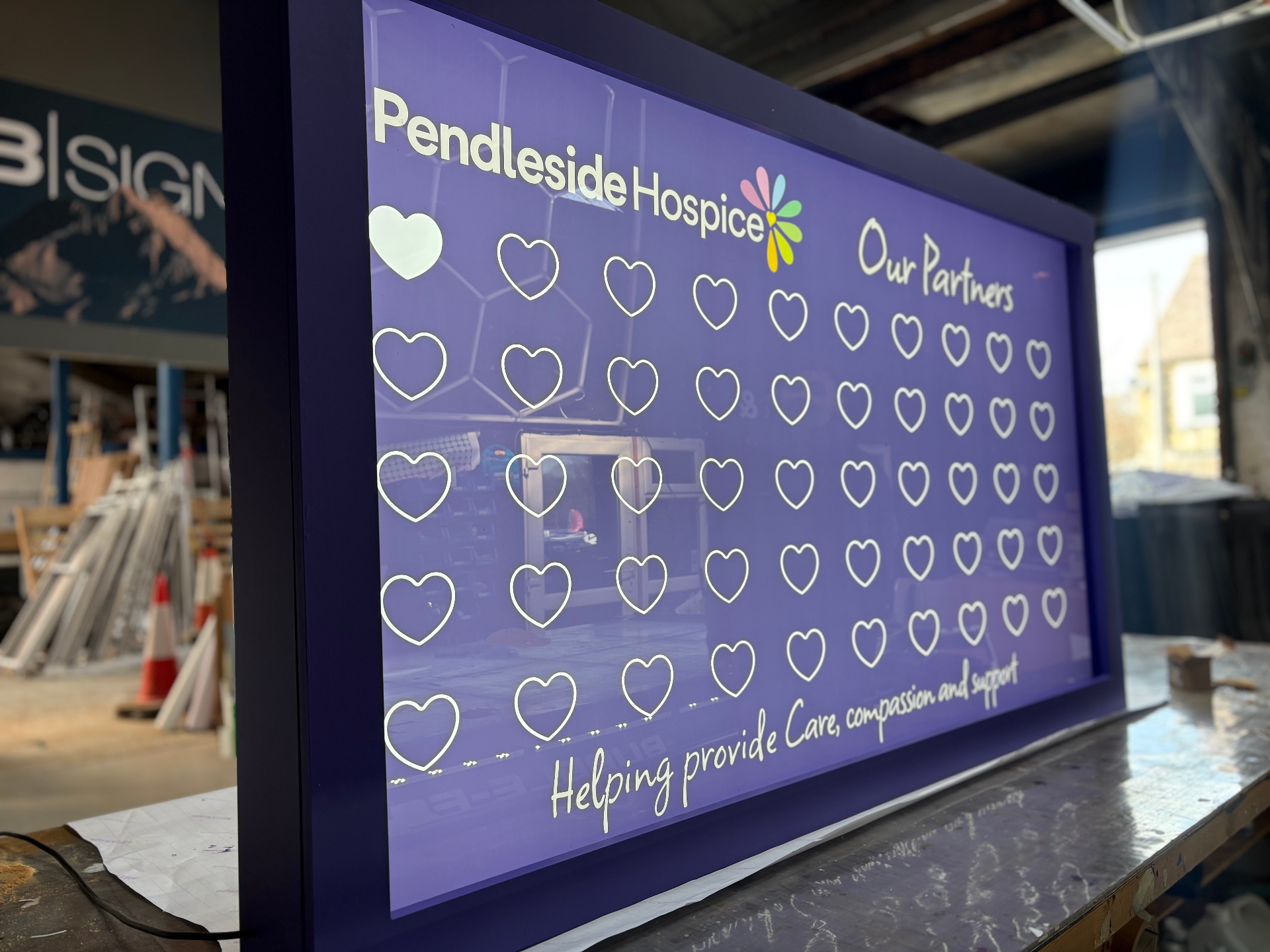 Bespoke illuminated Pendleside Hospice partners lightbox in the TCB Signage workshop