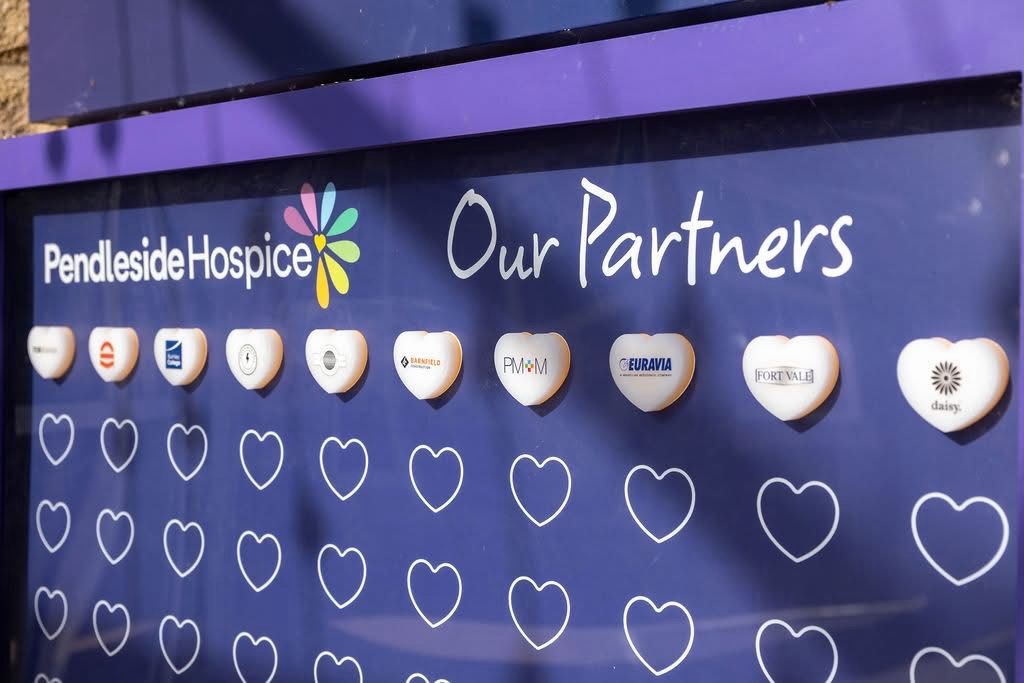 Close-up of the installed Pendleside Hospice 'Our Partners' heart display with branded acrylic hearts